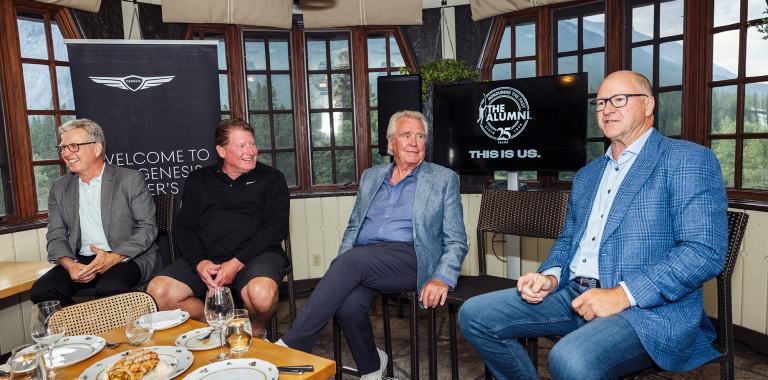 Quatre anciens joueurs de la LNH assis à une table avec une enseigne Genesis derrière eux