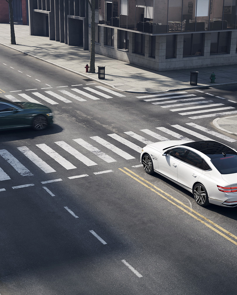  G80 stopped at a four-way intersection with a vehicle passing in front from the left.