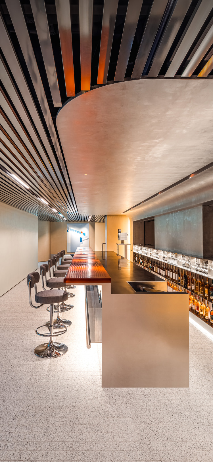 A side view of a whiskey and wine bar interior, where curved and linear ceiling designs blend harmoniously within an elegant, upscale ambiance.