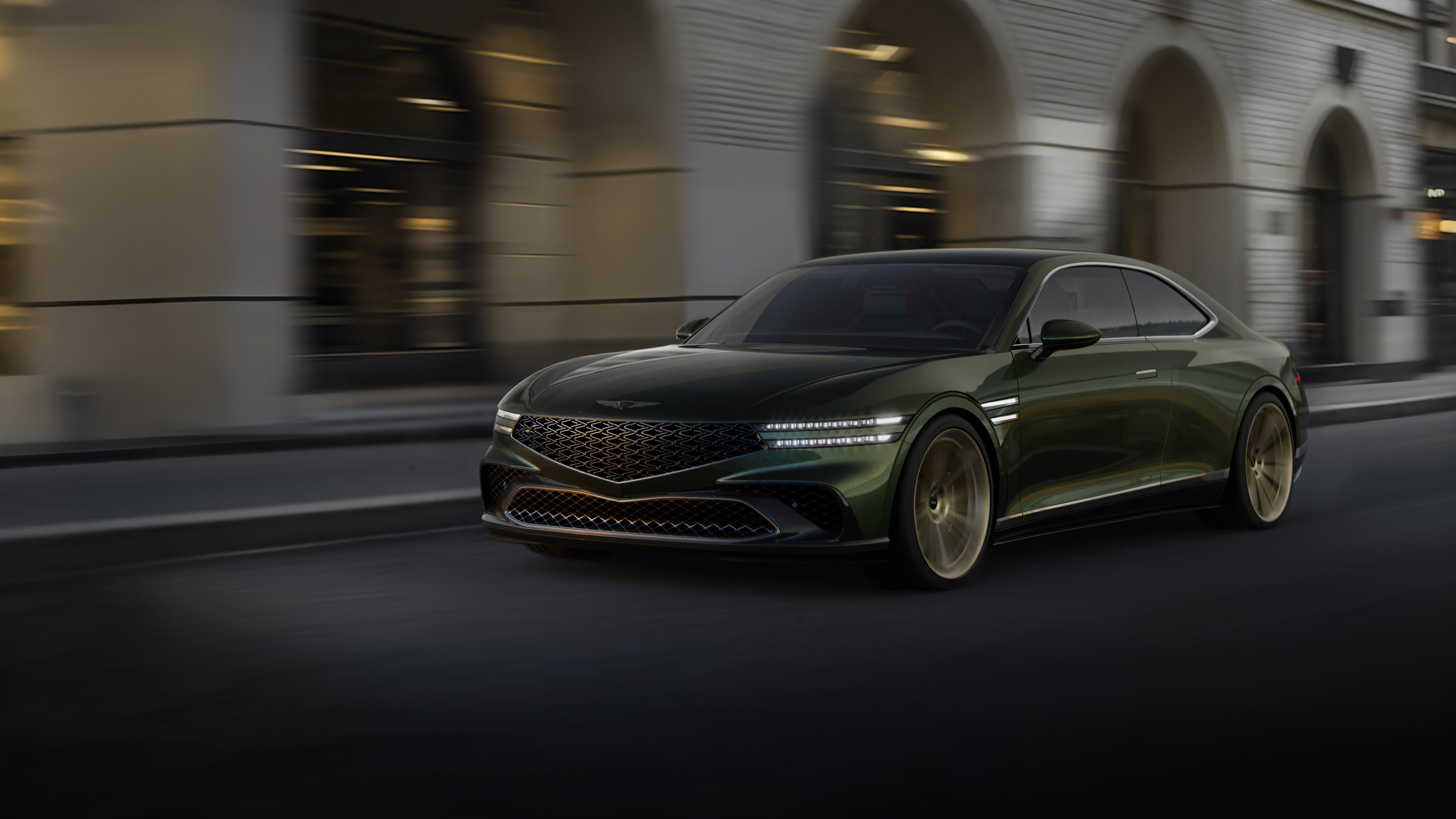 A Genesis X Gran Coupe is driving with a modern city in the background.