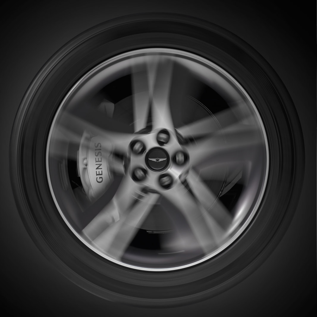 The Genesis logo is clearly displayed in the center of a rapidly spinning tire.