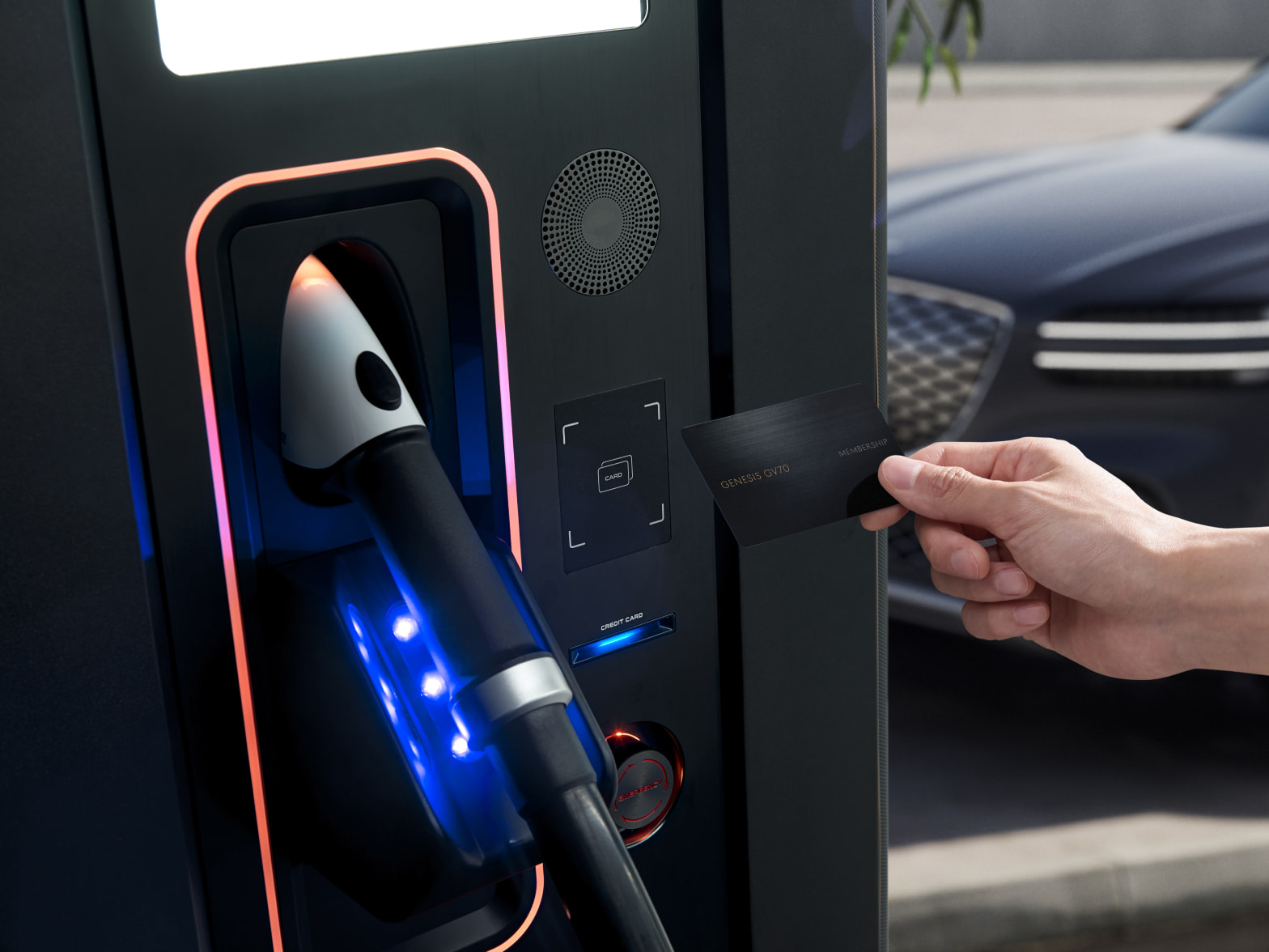 A hand holds a card near a device to use an EV charger at a public charging station.