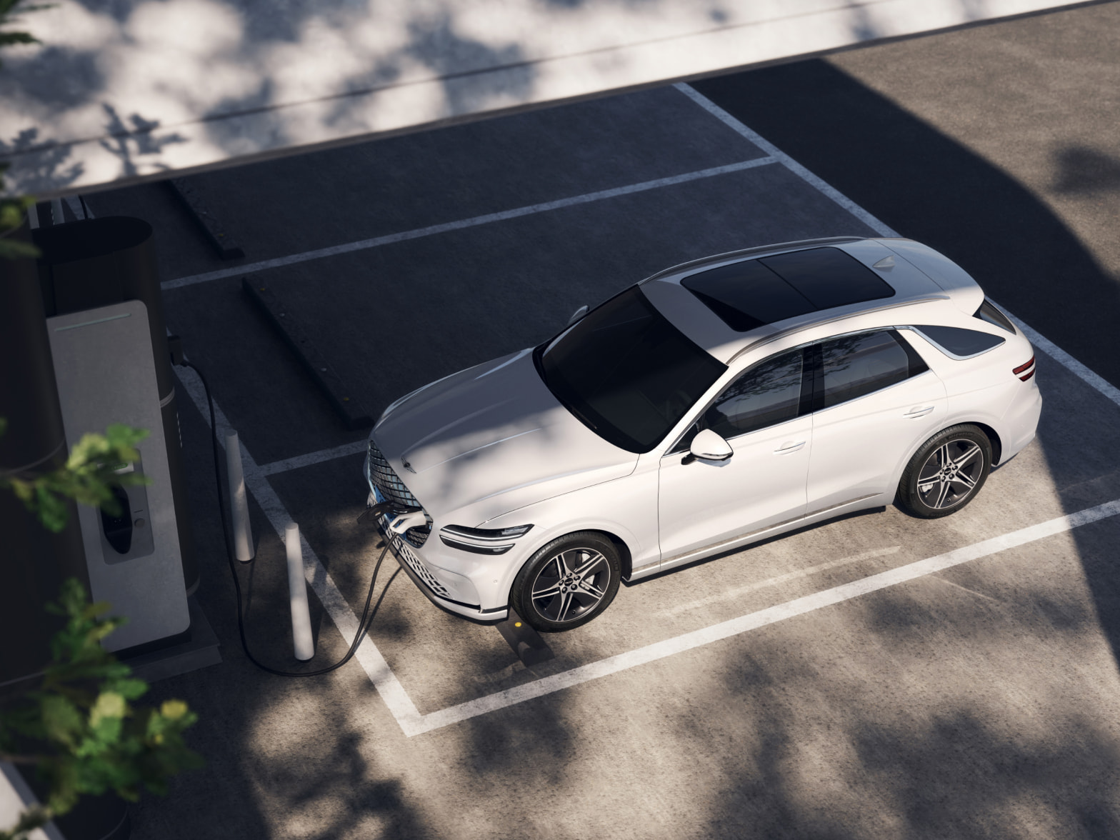 An aerial view from the left of a vehicle charging at a public charging station.