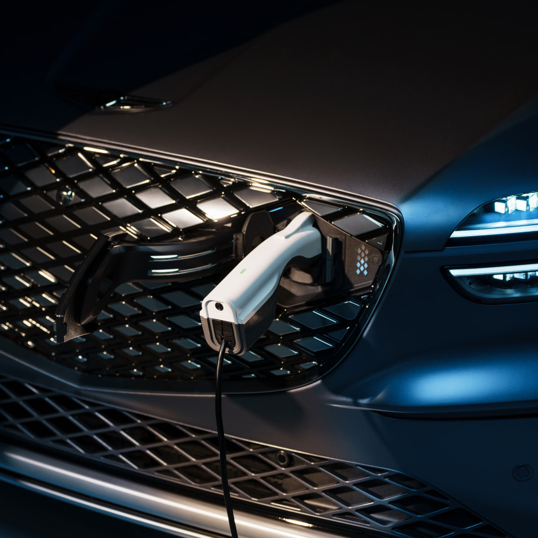 A charger is plugged into the front charging port of a Genesis electric vehicle.