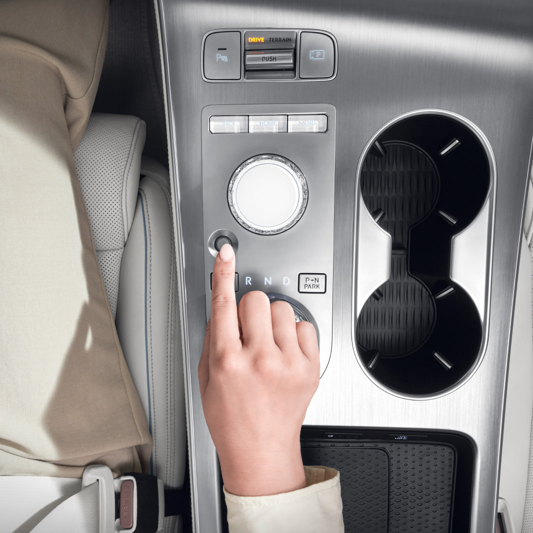 The driver has placed their finger on the fingerprint authentication system, located on the center console between the driver and front passenger seats.
