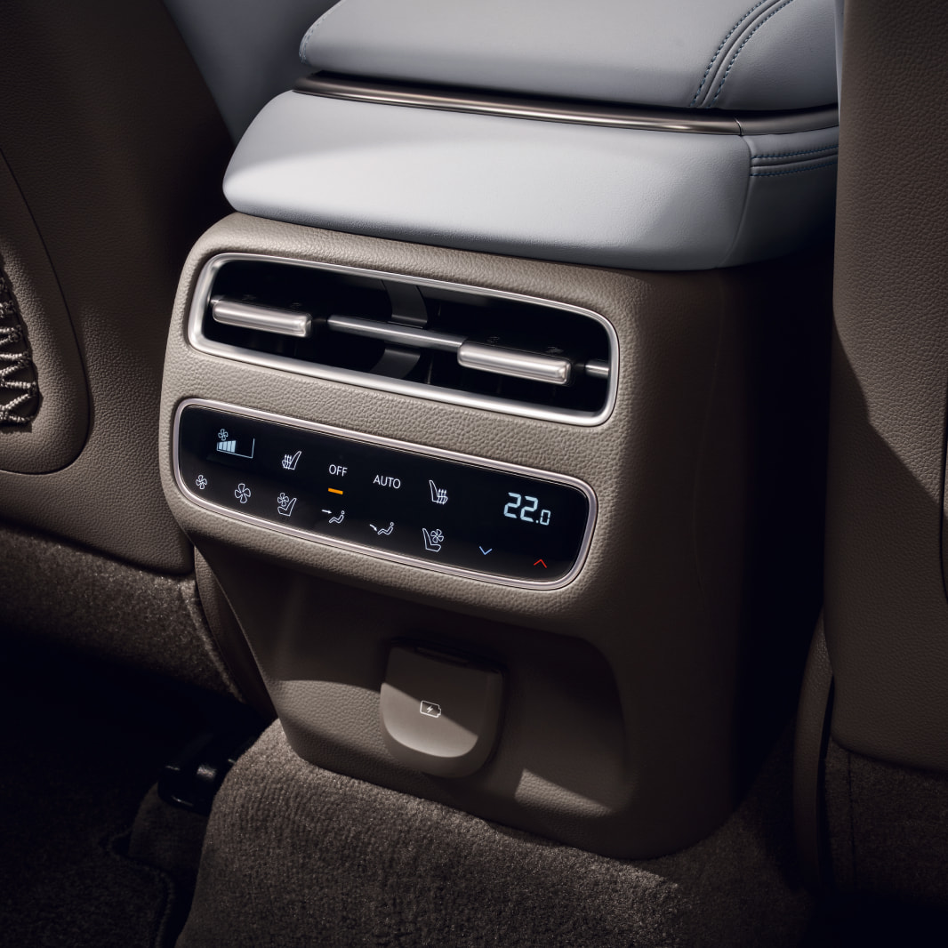 A view of the center console from the back seat. A touchscreen for controlling temperature and other settings is being used.