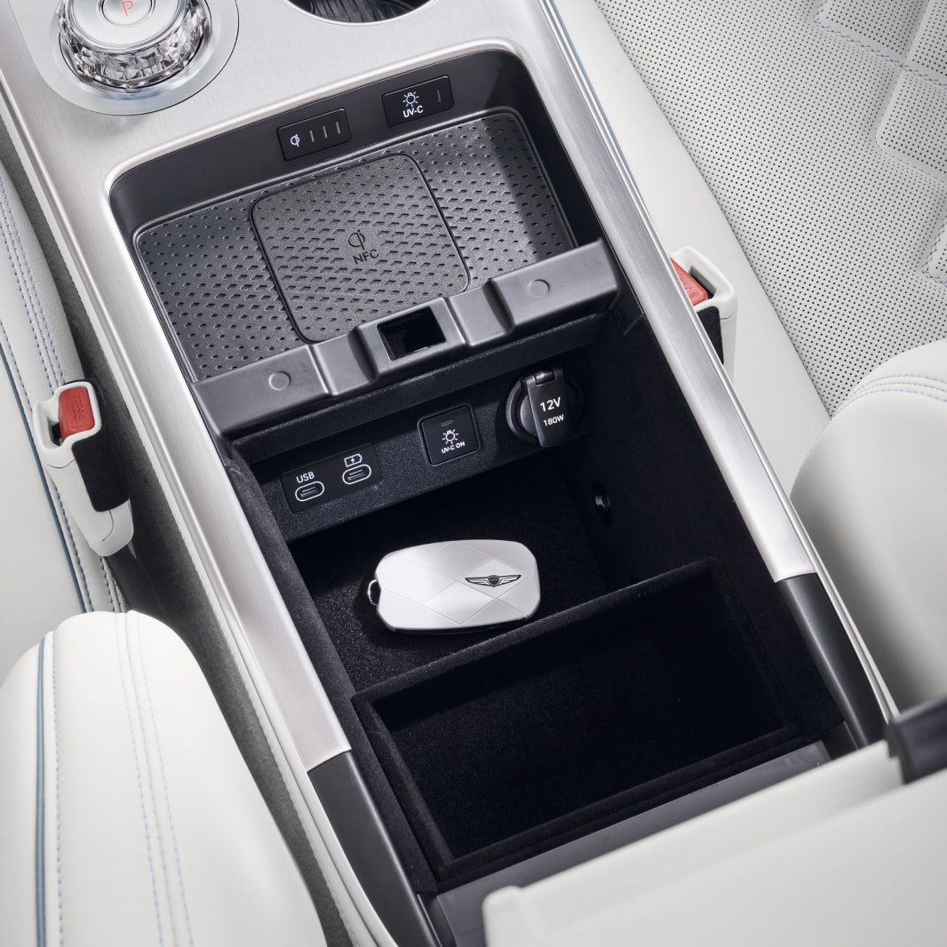 A view of the console between the driver and front passenger seats. The vehicle's physical key is stored inside the compartment.