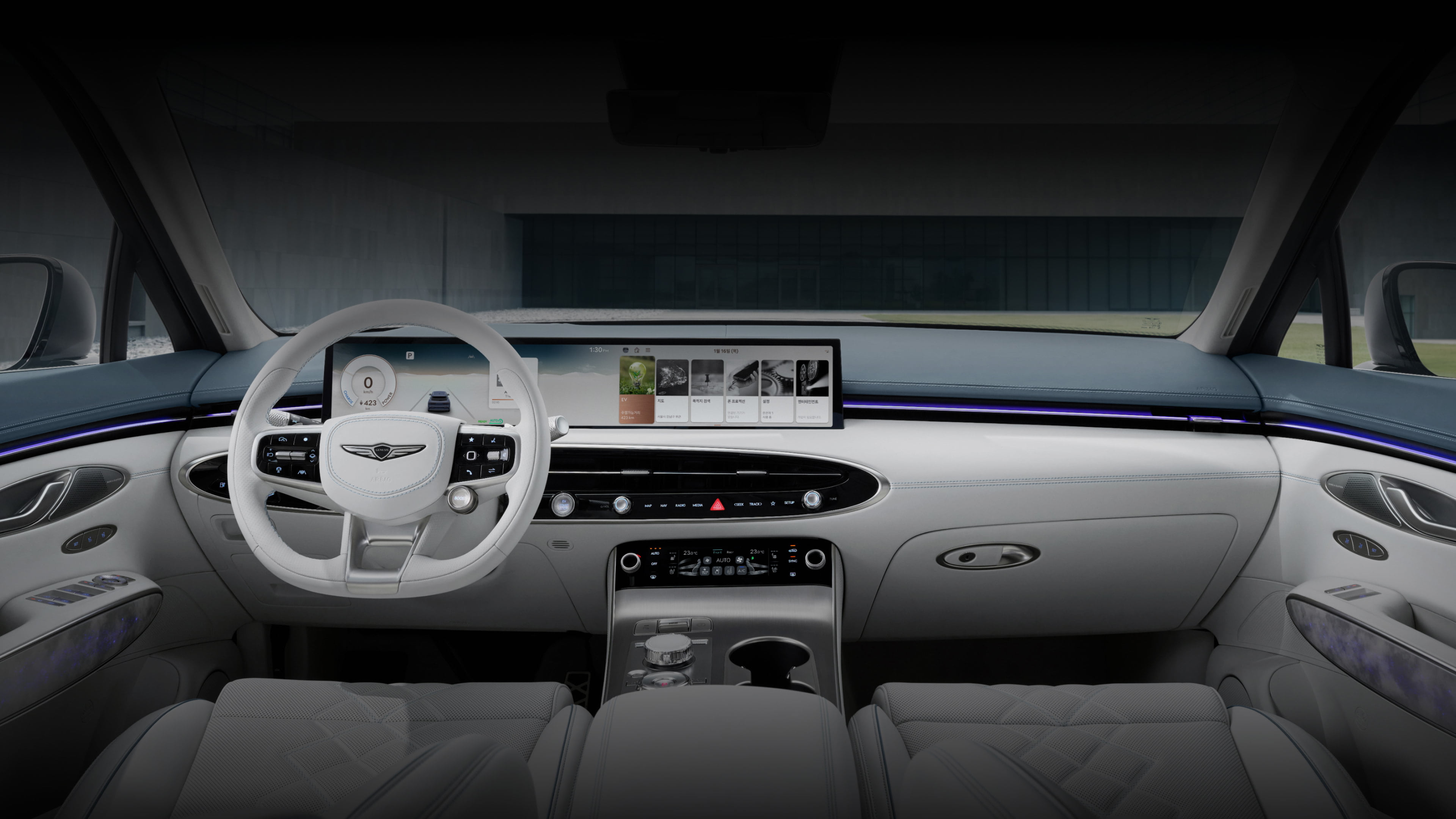 A detailed view of the driver and front passenger seats of the Electrified GV70, including a variety of buttons near the door handle as well as the steering wheel, display screen, and a cluster of control buttons between the driver and front passenger seats. 