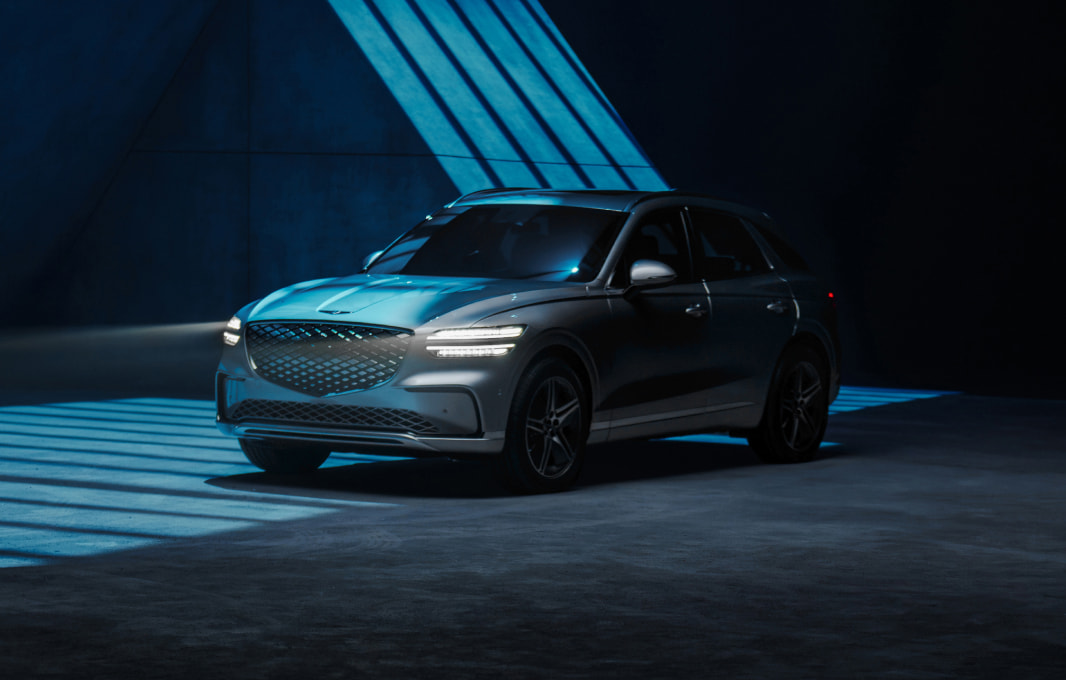 The Ceres Blue Electrified GV70 is parked in an outdoor space with an exposed concrete surface.