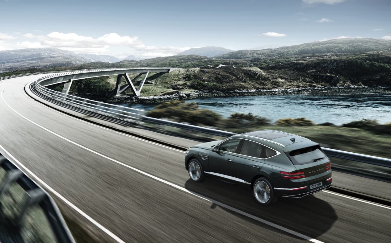 Storr Green GV80 Coupe driving fast on the highway while maintaining a safe distance from the vehicle in front.