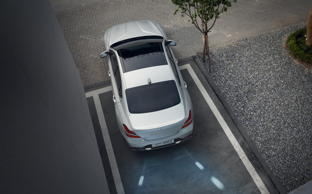 A guide lamp illuminates the ground from the rear of a parked Uyuni White G70.