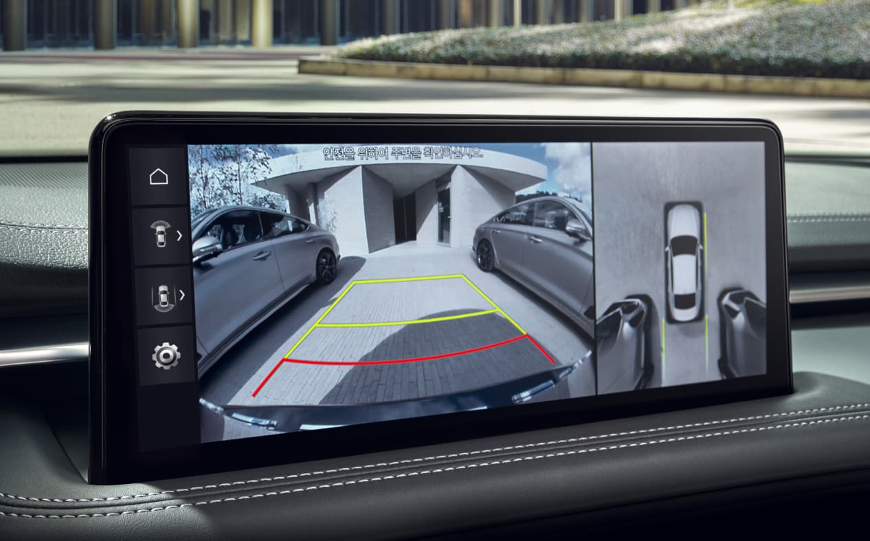 The infotainment display shows a video of the surroundings as Uyuni White G70 pulls out of the parking lot.