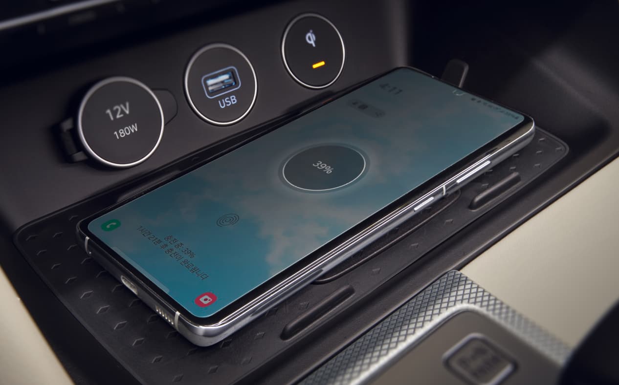A smartphone is being wirelessly charged on the charging pad in the front.