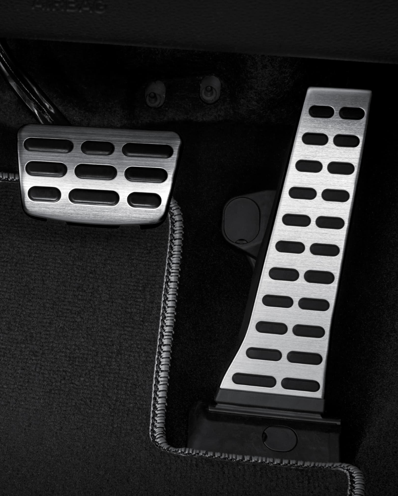 A close-up of the metal pedals and foot rest plate under the driver's seat. 