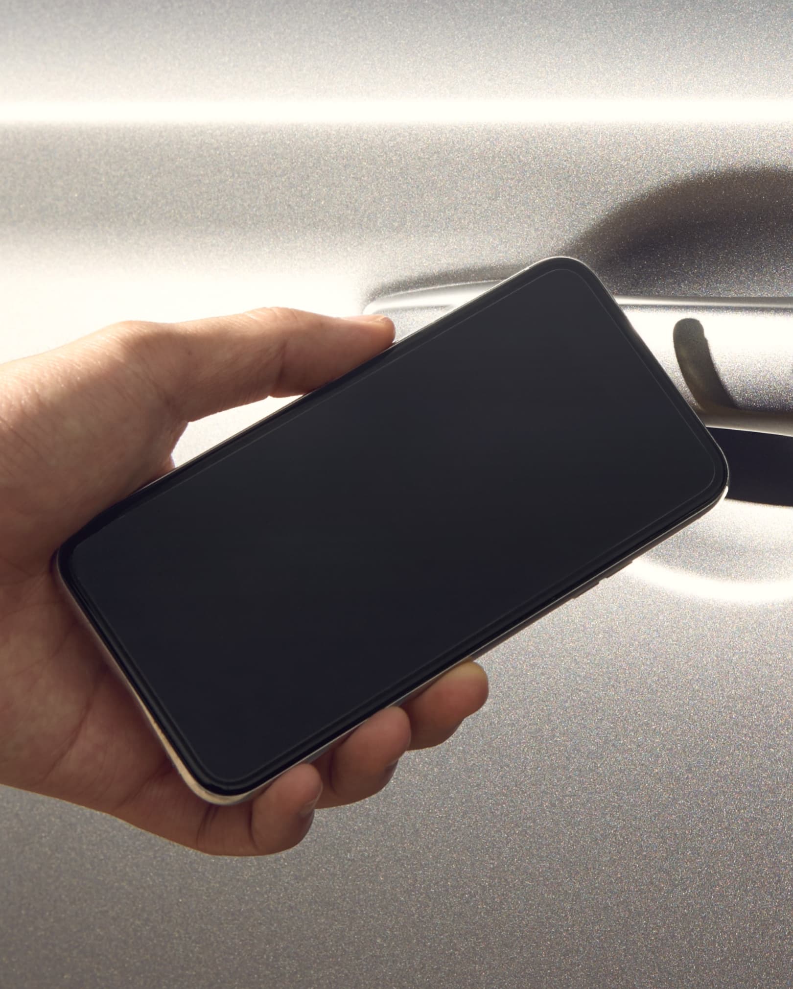 Using the Genesis Digital Key app while holding a smartphone close to the car door.