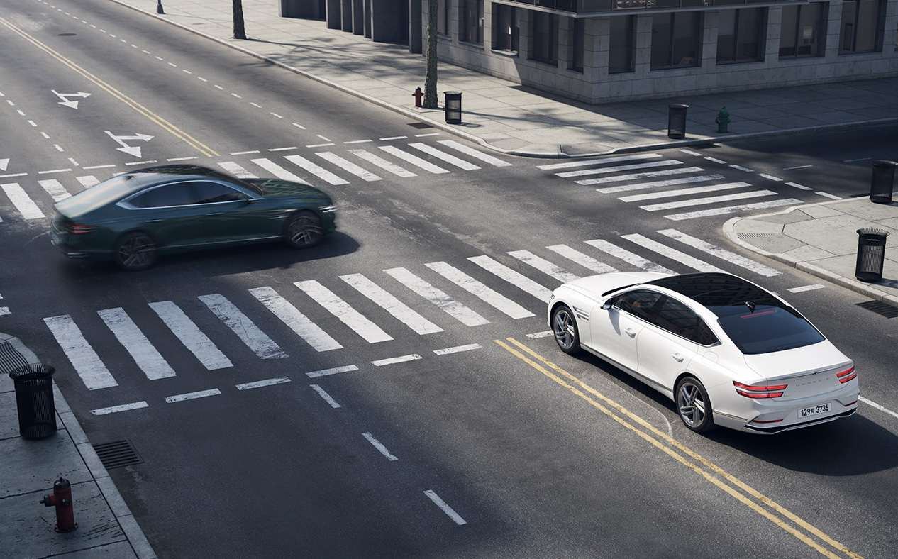 G80 stopped at a four-way intersection with a vehicle passing in front from the left.