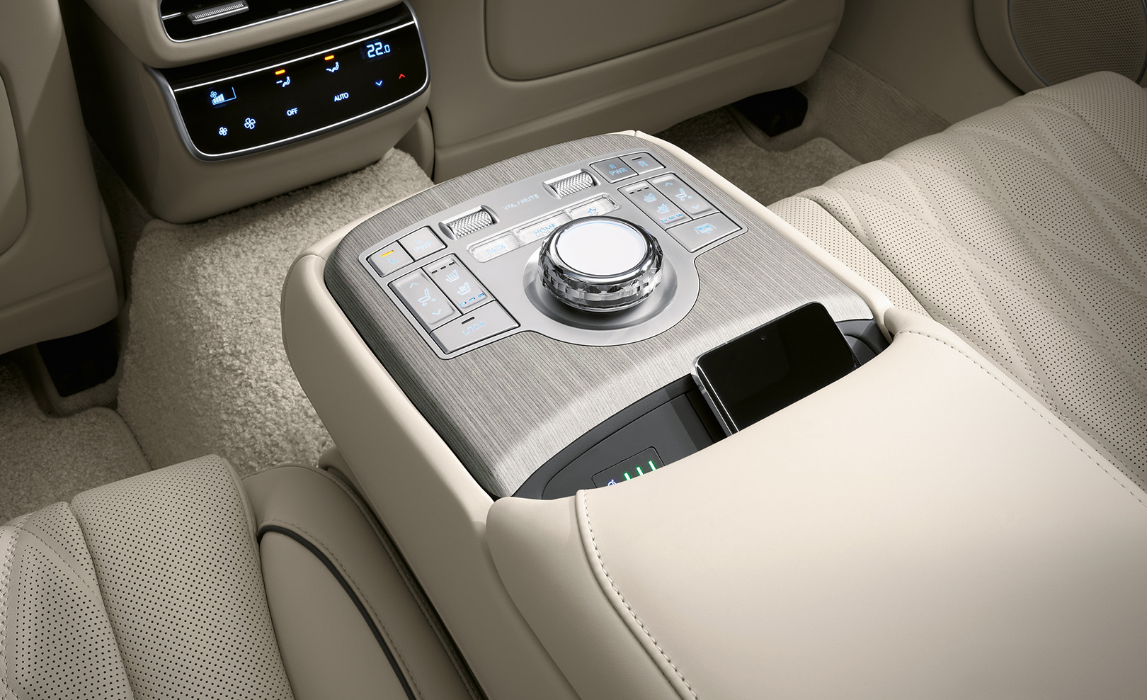 A smartphone charges wireless on the second row armrest.