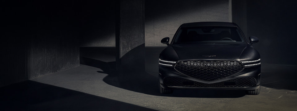 The G90 Black is parked in a dark space with its headlights on, facing forward.