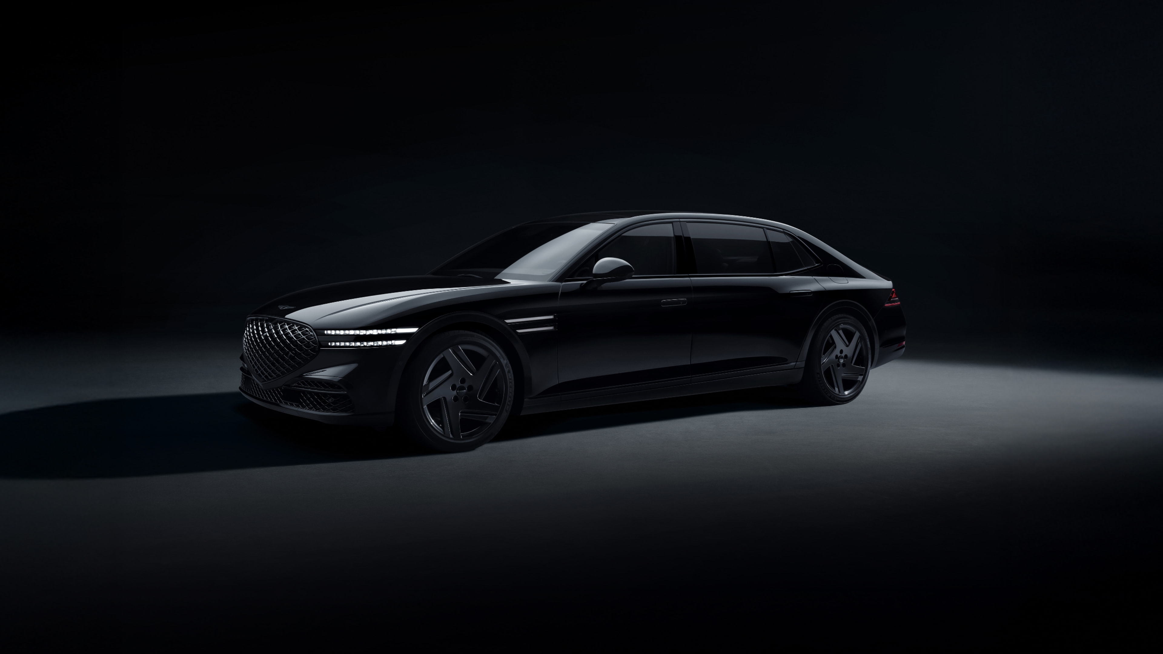 A front/side view of the G90 Long Wheel Base Black long body, parked on illuminated ground in a dark space.