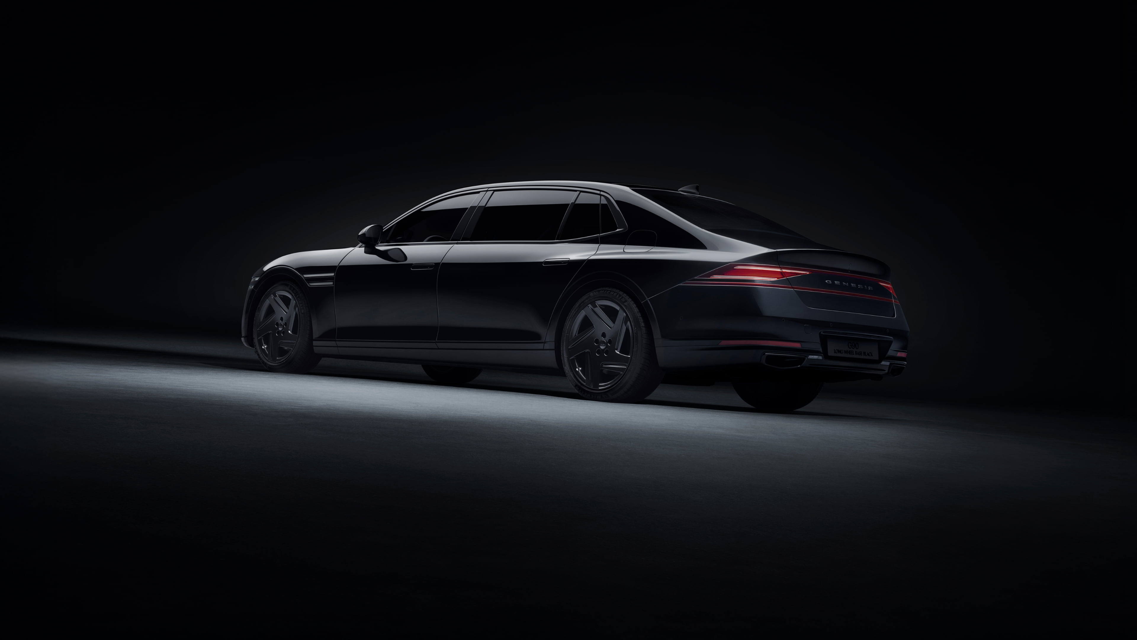 A rear/side view of the G90 Long Wheel Base Black long body, parked on illuminated ground in a dark space.