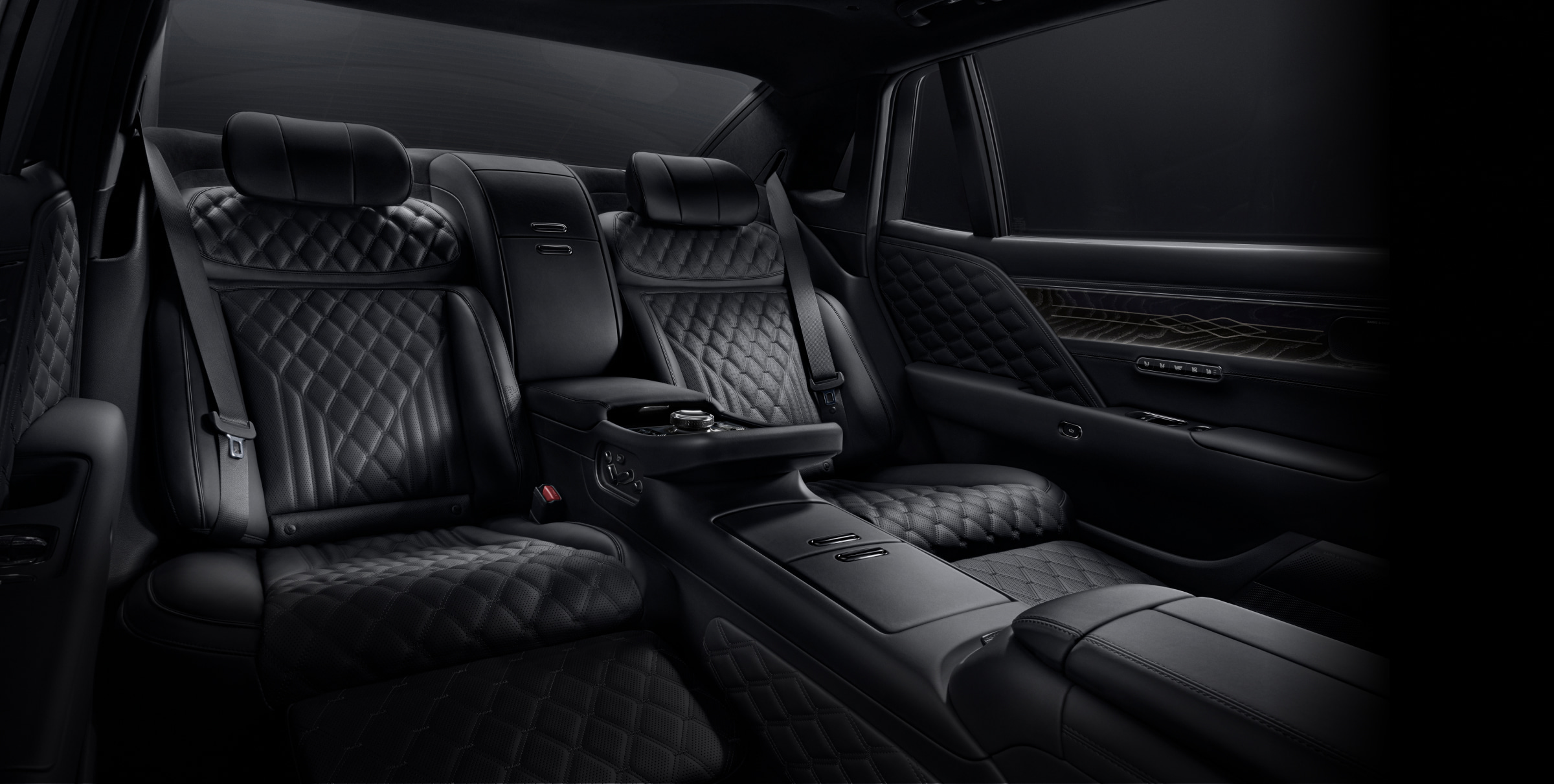 From the front passenger seat, looking backward, the rear seat interior unfolds. Every element is in black, highlighting the quilted pattern of the leather seats.