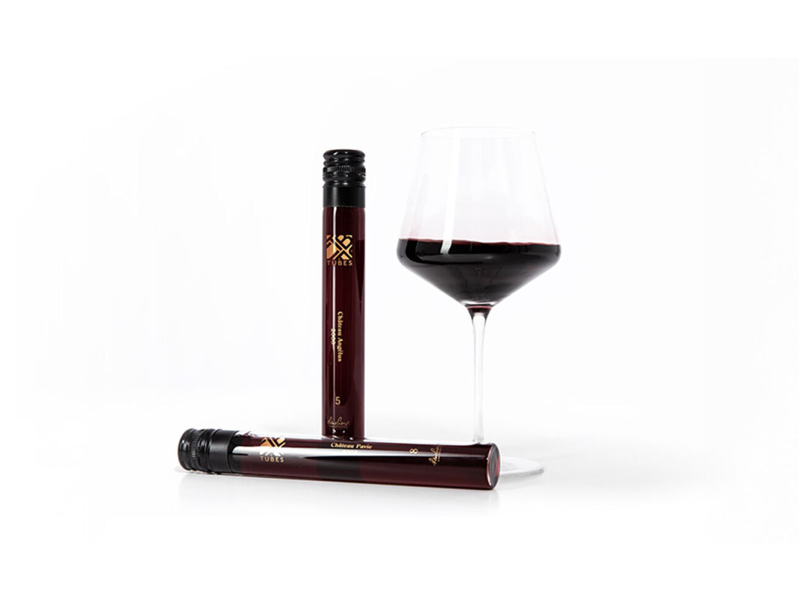 Two wine tubes and a glass of wine are displayed. One wine tube is lying on the surface, while the wine glass is half-filled.