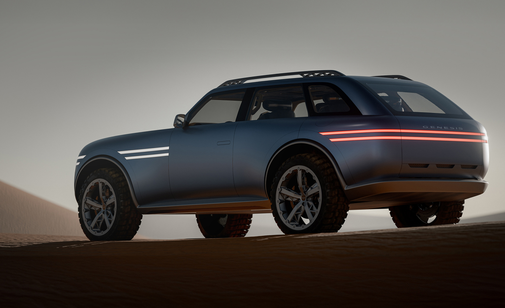 The Genesis X Gran Equator concept is parked in the middle of the desert, showing its side and rear. The two-line lamps at the front and rear are illuminated.