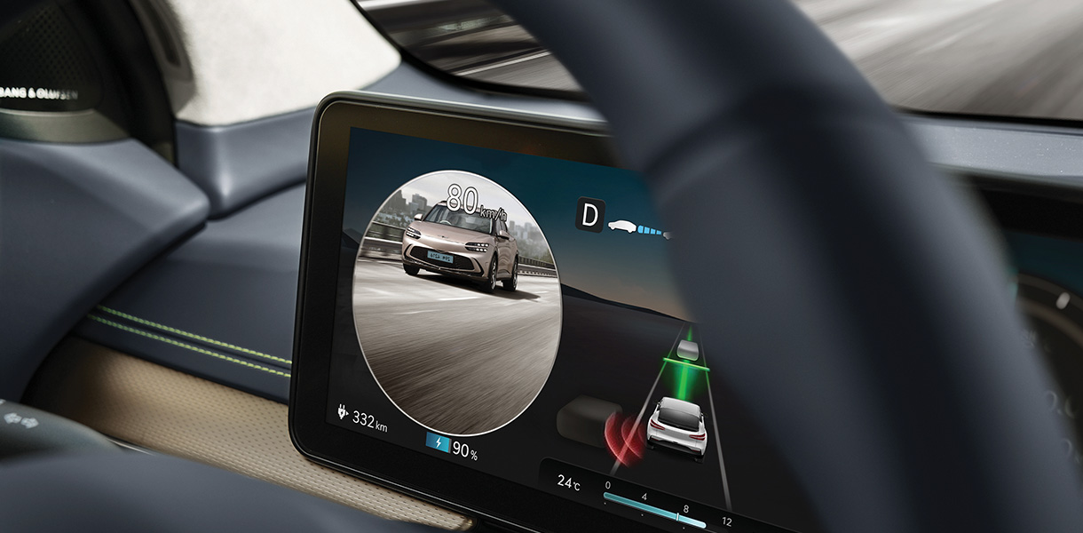 The rear side monitor shows the Atacama Copper colored GV60 driving on the road.