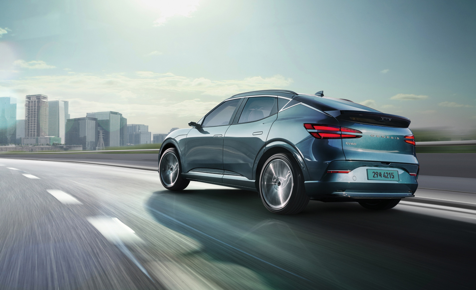  With a modern building in the background, you can see the rear of the GV60 driving fast on the highway.