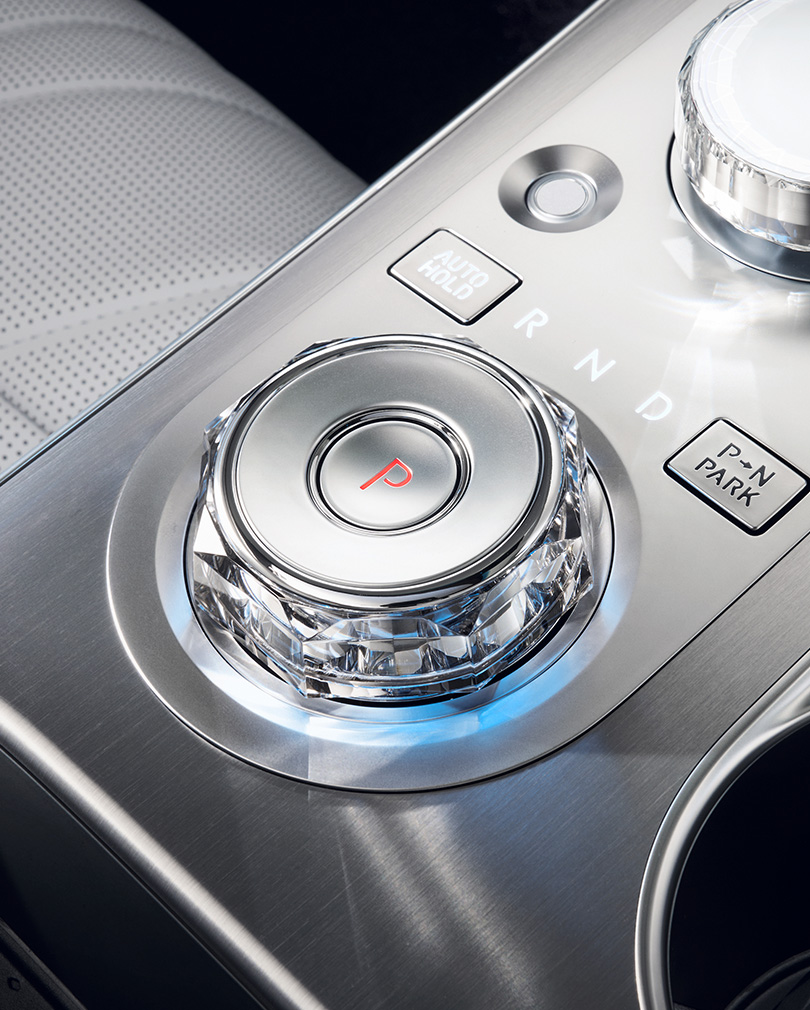 The electronic shift dial of the GV70, illuminated with a subtle blue light in the form of an octagonal crystal, is enlarged. The letter 'P' in red is written within the central circle.