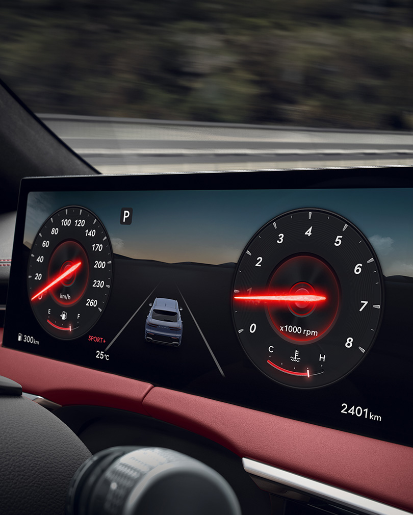 The instrument cluster inside the wide display screen is enlarged. The gauge needles are highlighted in red.
