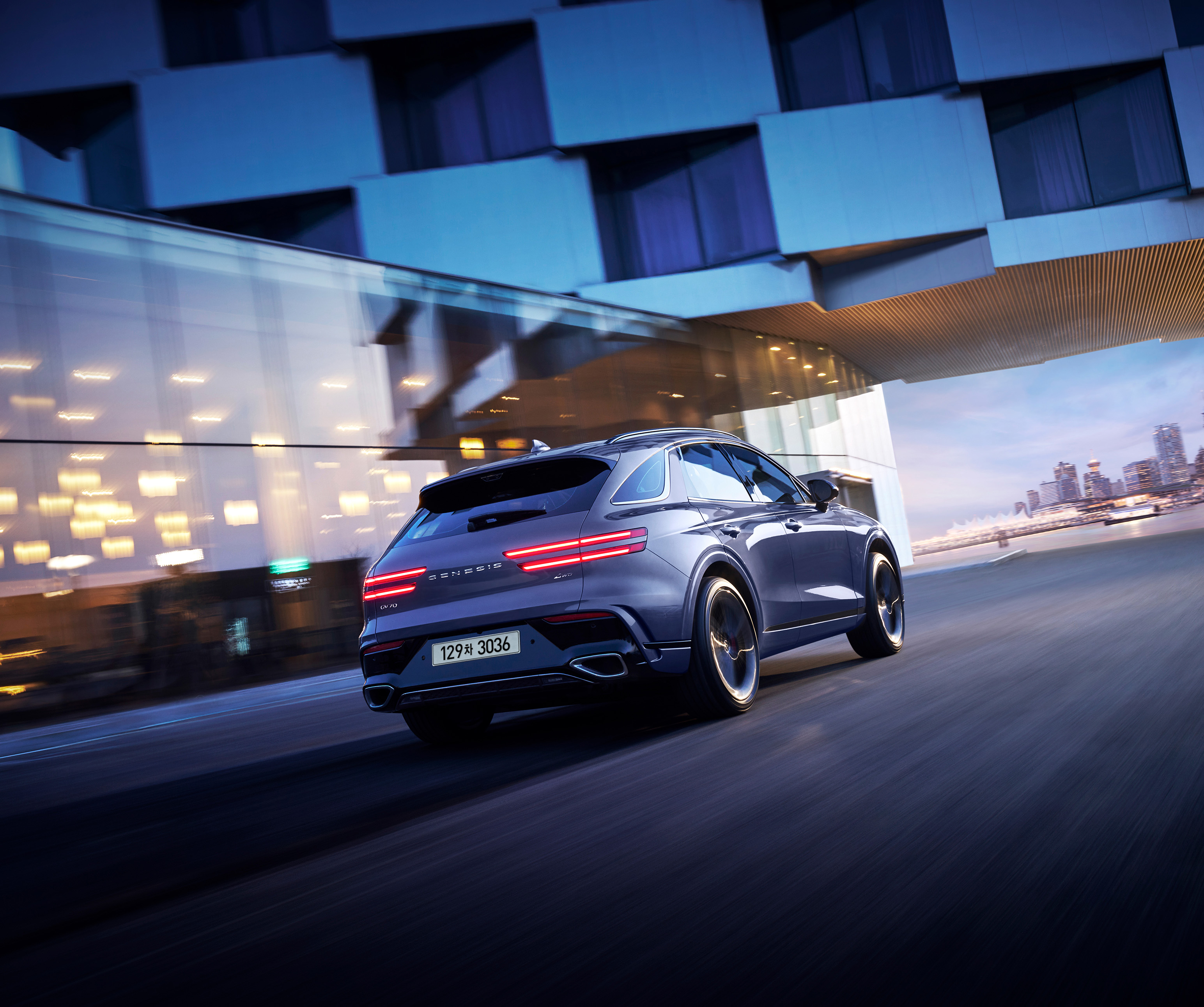 This is a view from the rear of the GV70 driving through a city illuminated by city lights at night.
