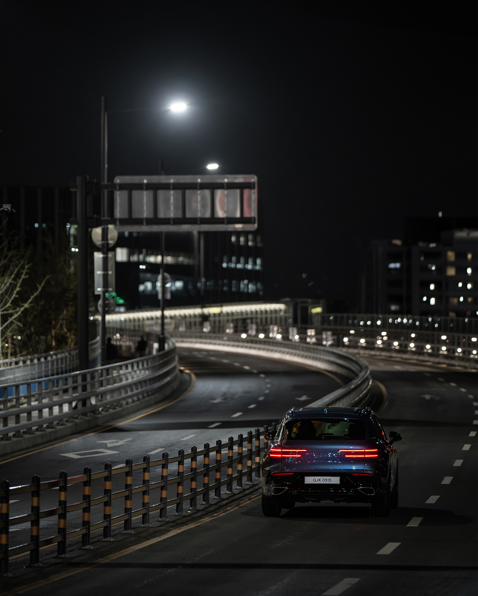 You can see the rear view of a Uni White GV70 driving on the highway.