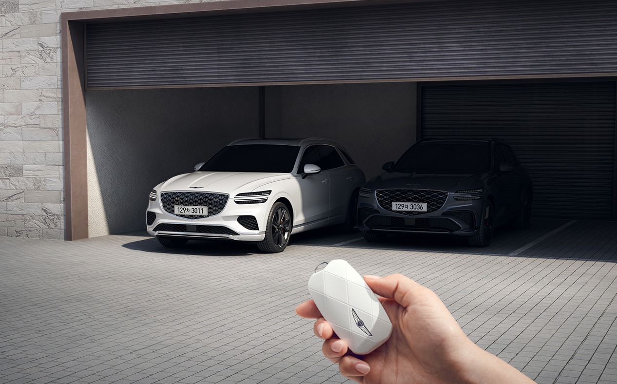 Outside the vehicle, the driver is using the smart key to park the GV70 in the garage.