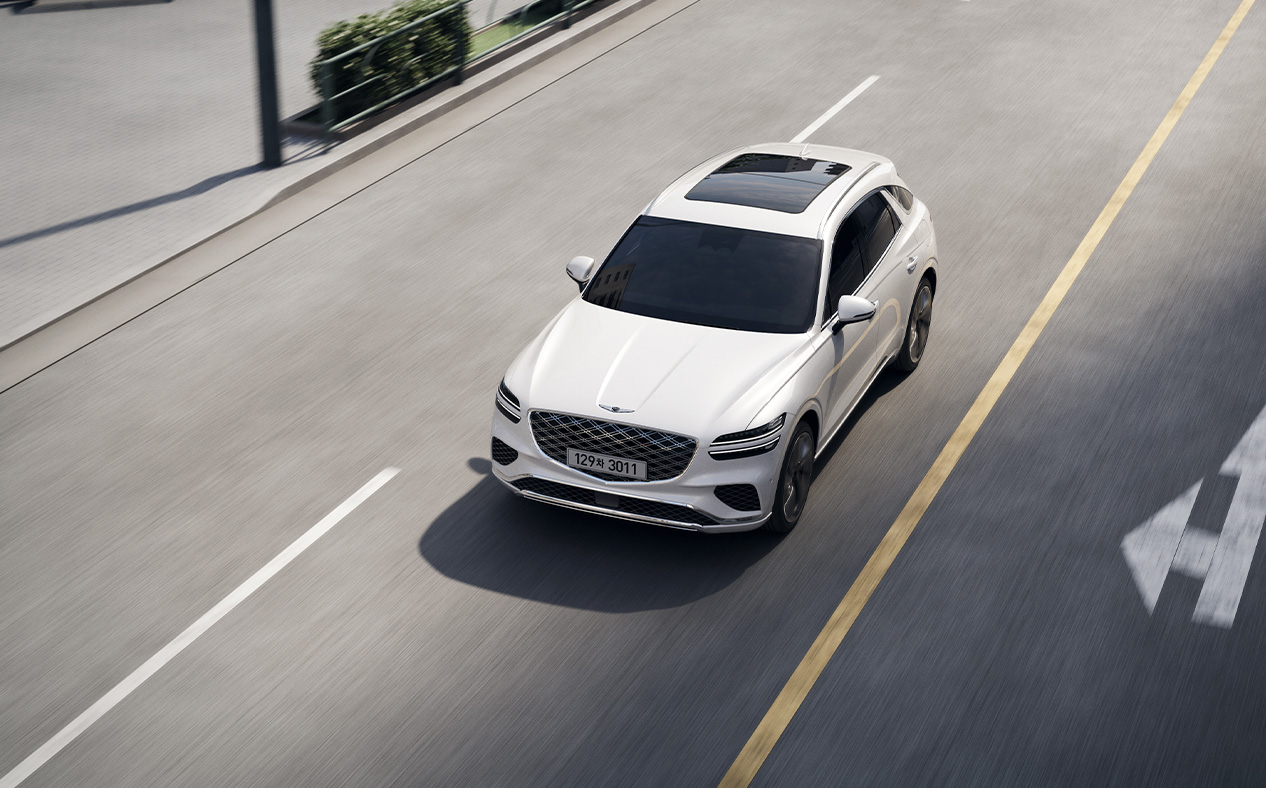 The GV70 is driving on the road, staying in its lane.