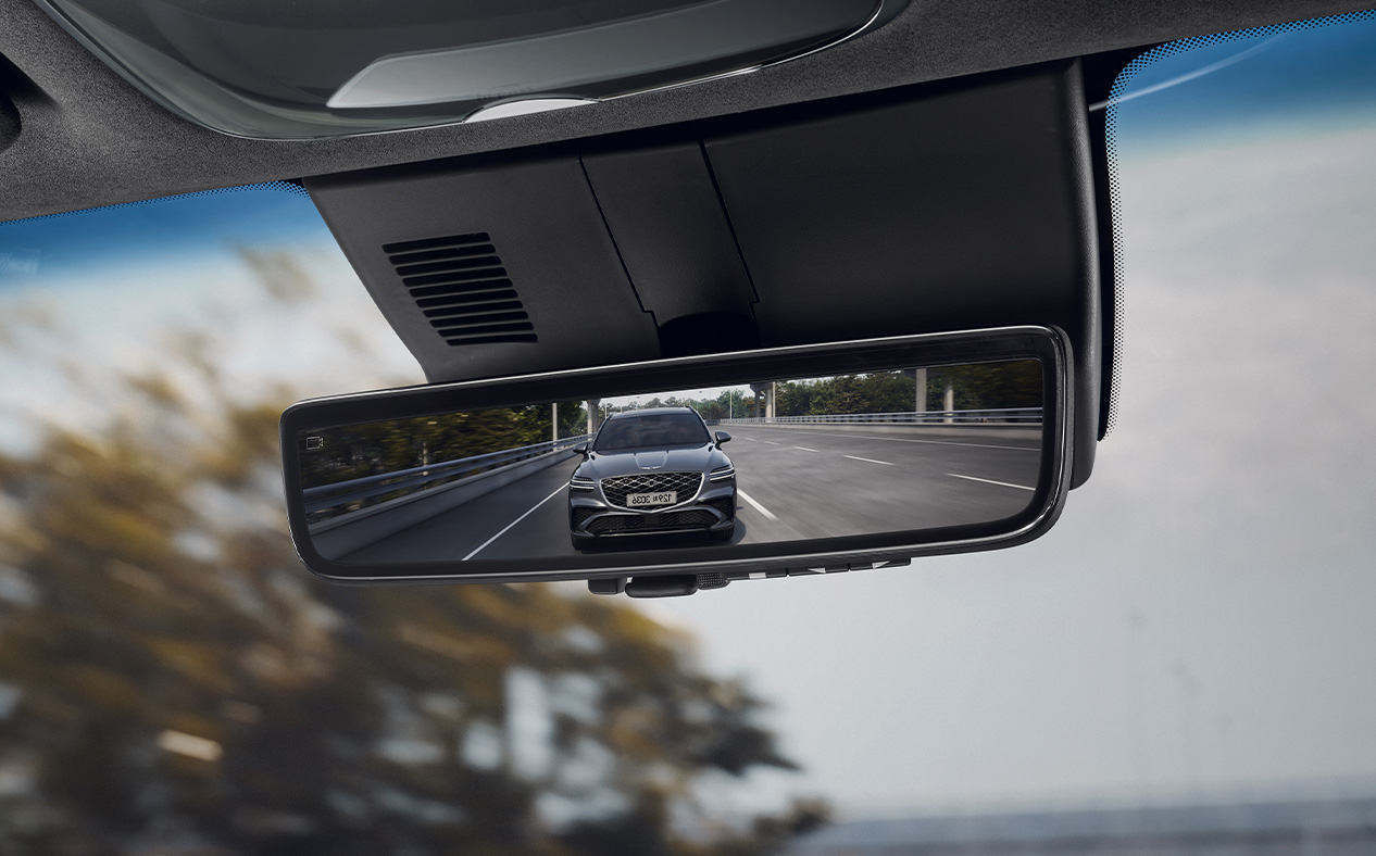 The front view of the car behind is reflected in the vehicle's rearview mirror.