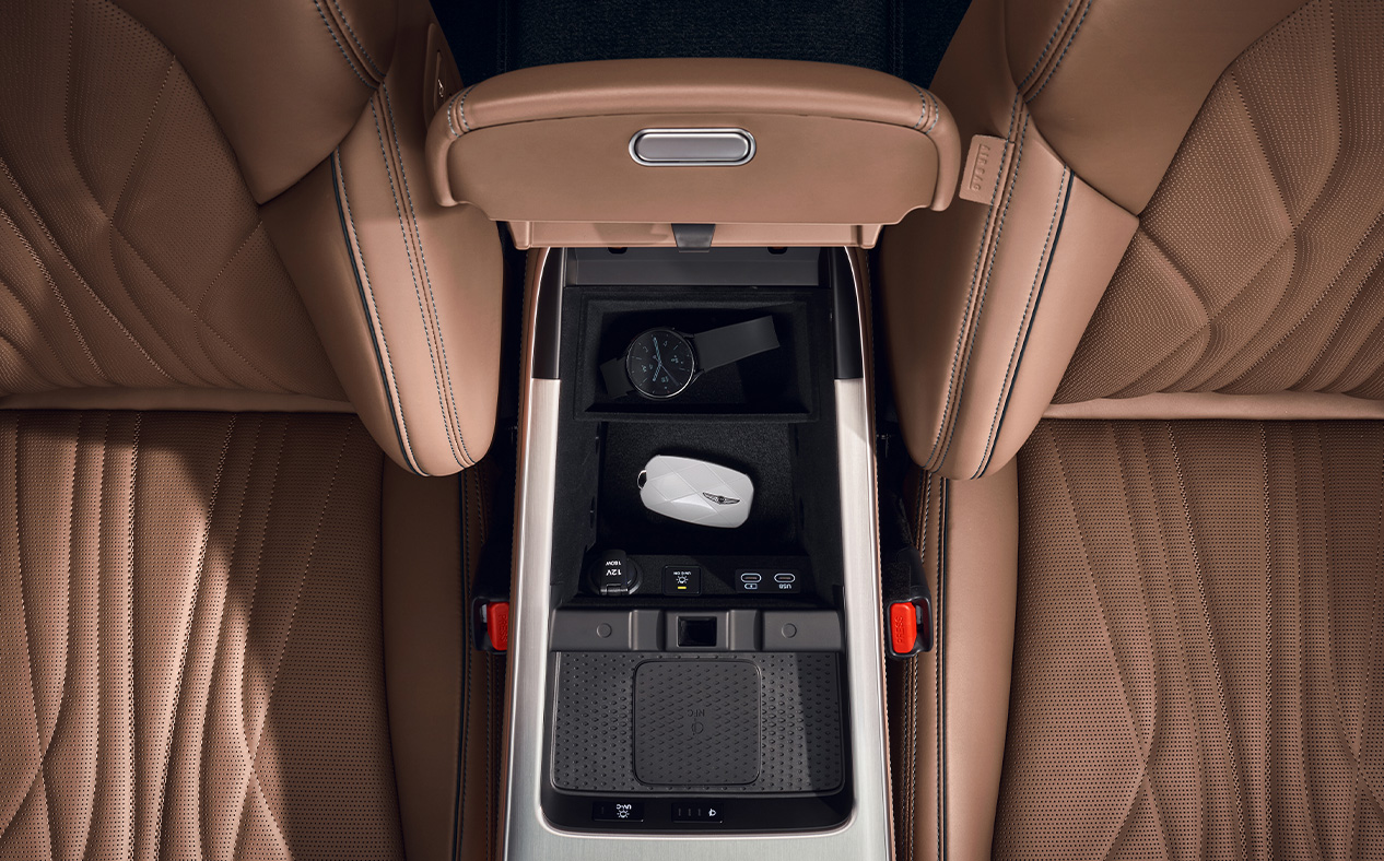 The armrest storage compartment between the driver's seat and the passenger seat is open, revealing its interior.