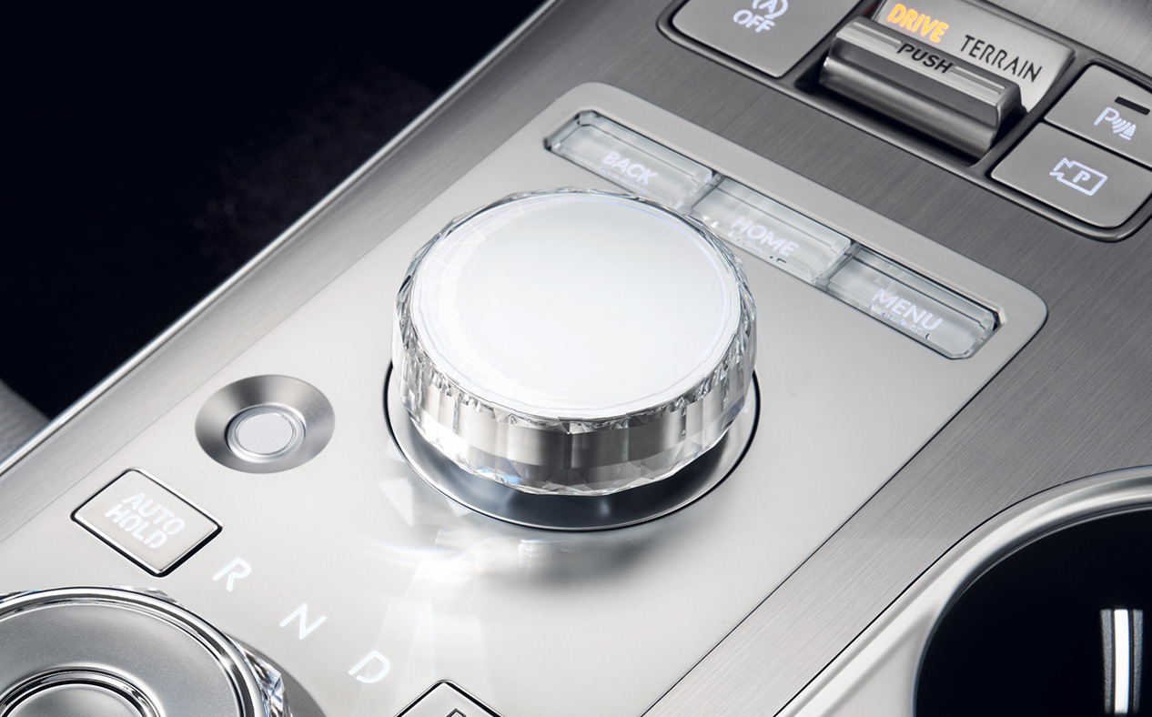 The integrated controller located between the driver's seat and the passenger seat is highlighted. Various buttons for control are present alongside the controller.