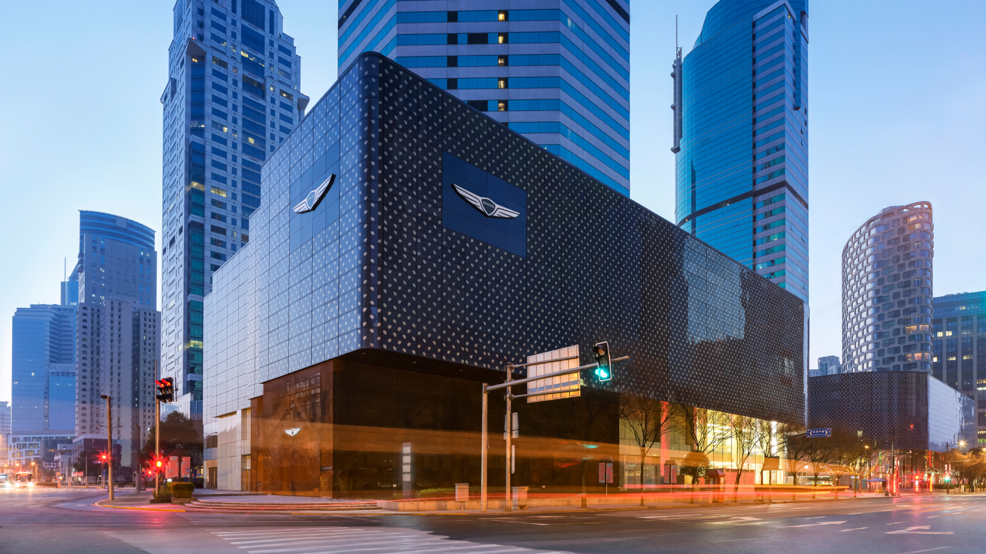 An exterior view of Genesis Studio Shanghai in the middle of the city. The building is designed with dotted blue lights. An exhibition is taking place on the first and second floors.