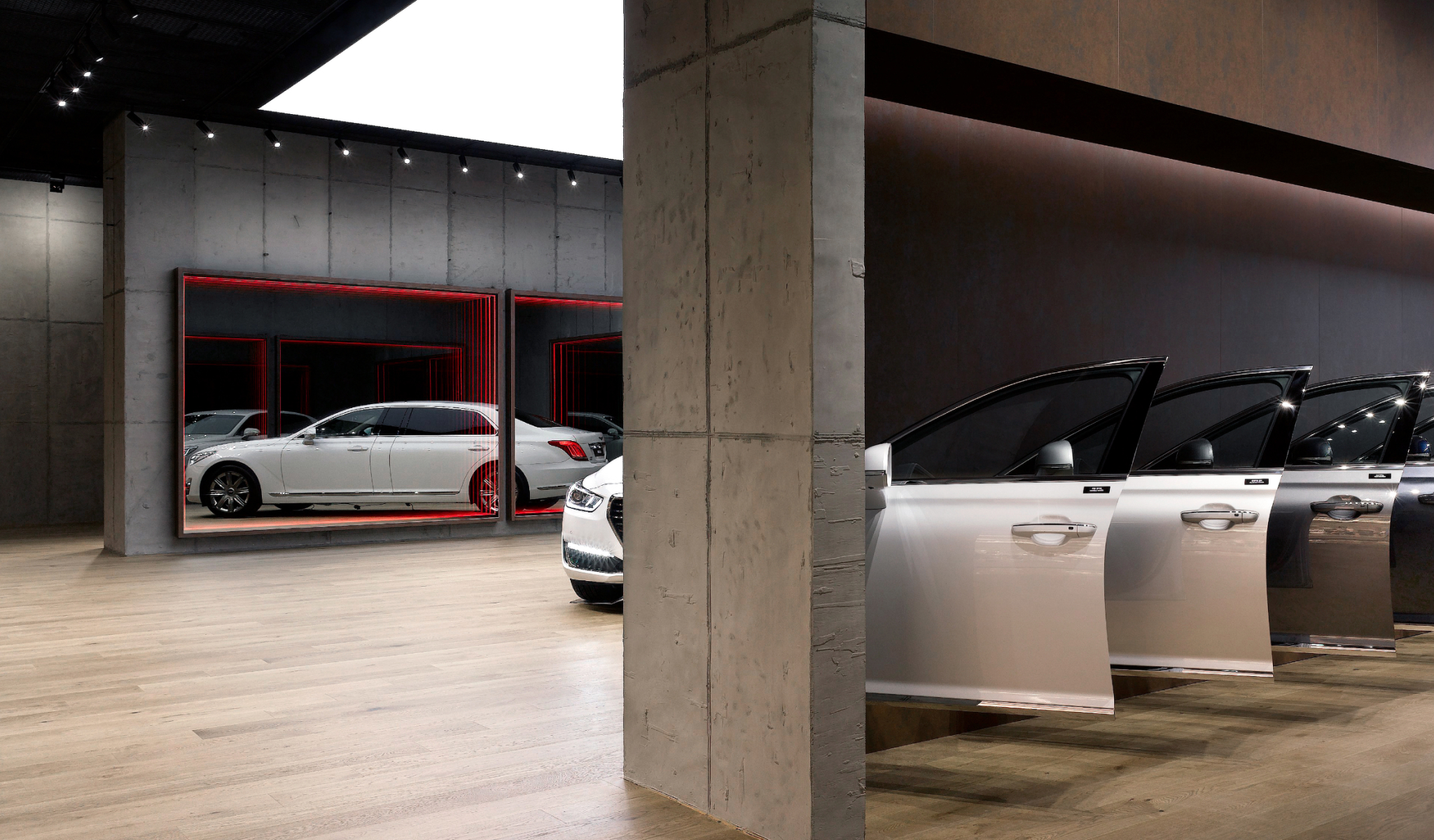 The back half of a black Genesis vehicle sits next to a concrete wall.