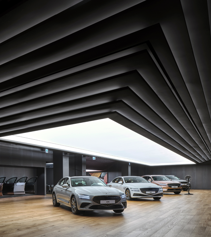 Four Genesis vehicles on display under a large ceiling light.