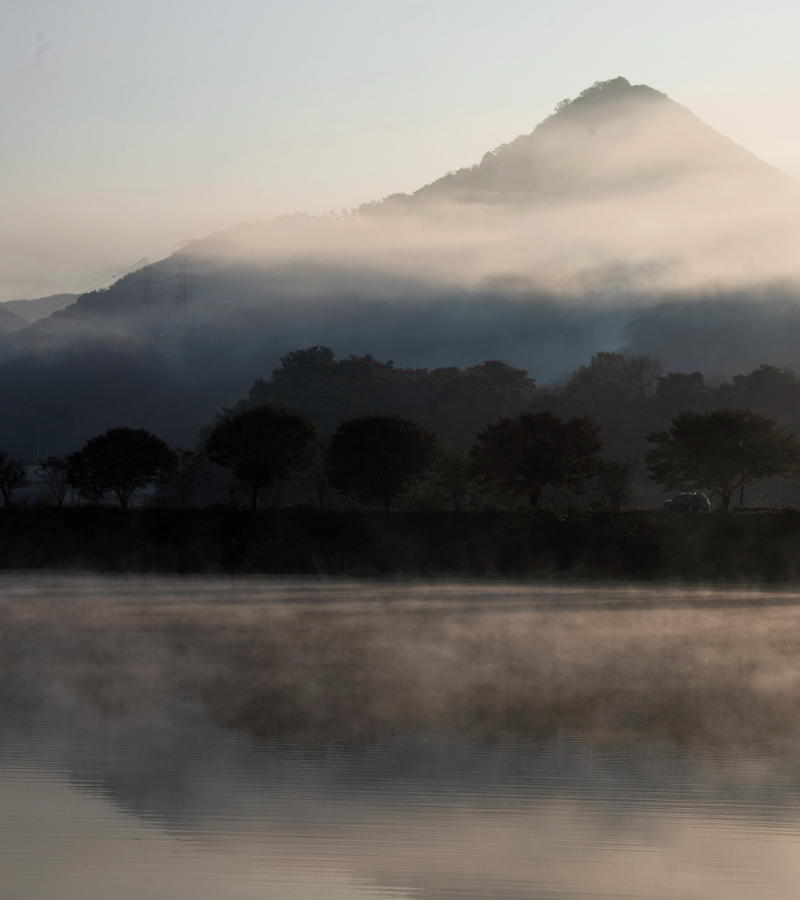 A thick fog hangs over mountains and a river.