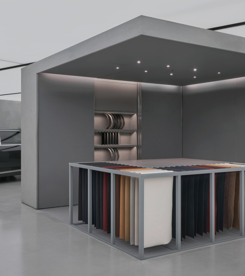 A cube-shaped space with Genesis exterior and interior colors on display. A Genesis vehicle peeks out from behind.