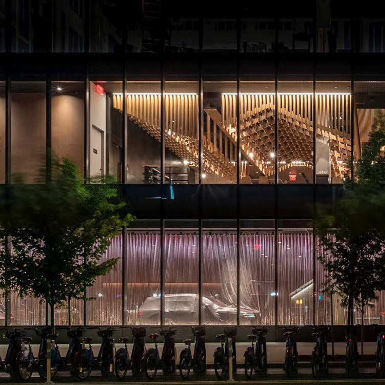 An exterior view of the Genesis House building in New York City with bright lights on inside.