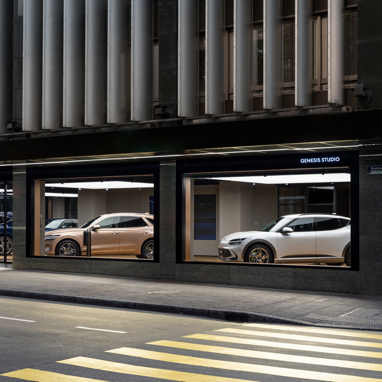 An exterior view of the Genesis Studio Geneva building in Switzerland with multiple Genesis vehicles inside.