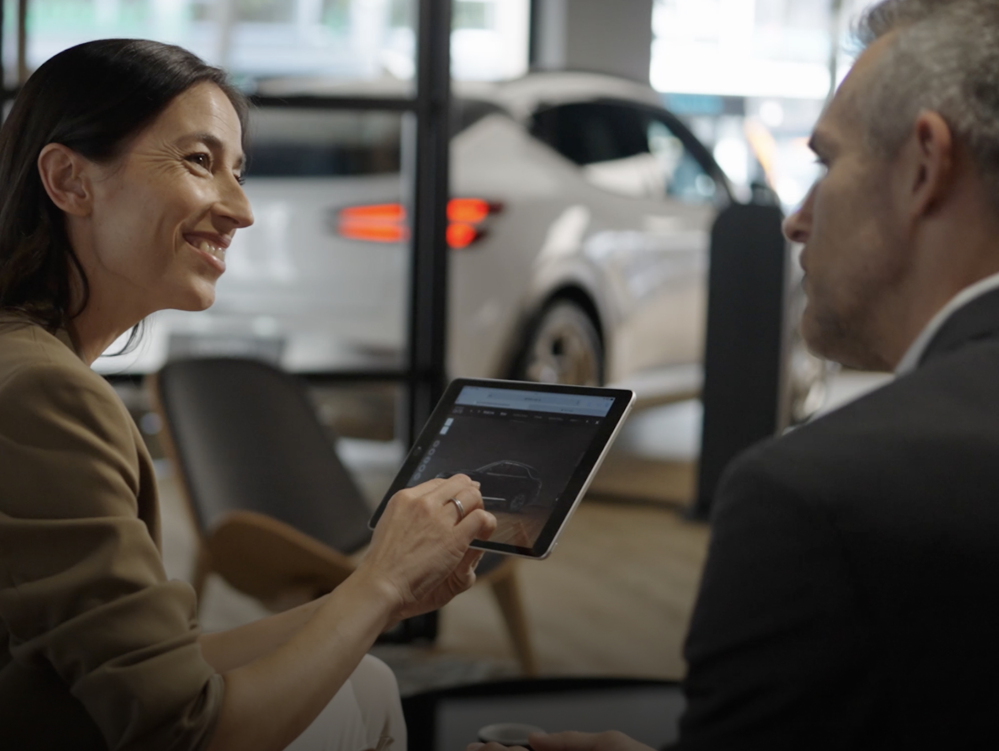 A Genesis curator shows a guest vehicle information on a tablet.